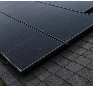Black rooftop solar panels on asphalt shingle roof